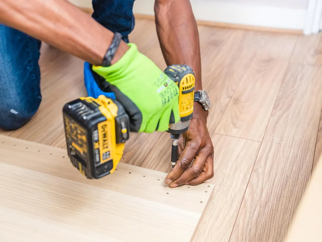 Installer securing a laminate floor plank with a drill