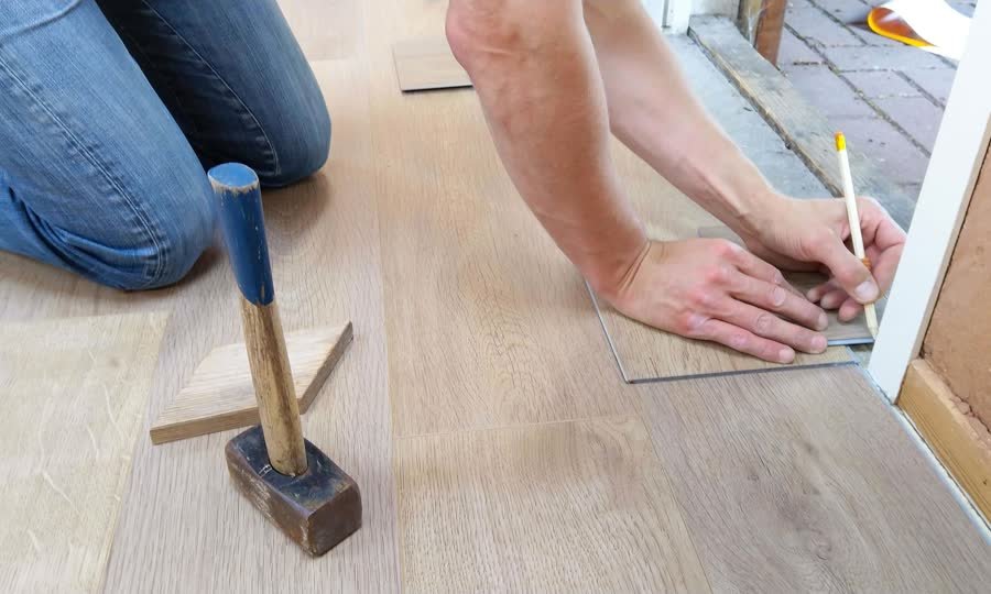 Installer fitting a hybrid flooring plank near a doorway