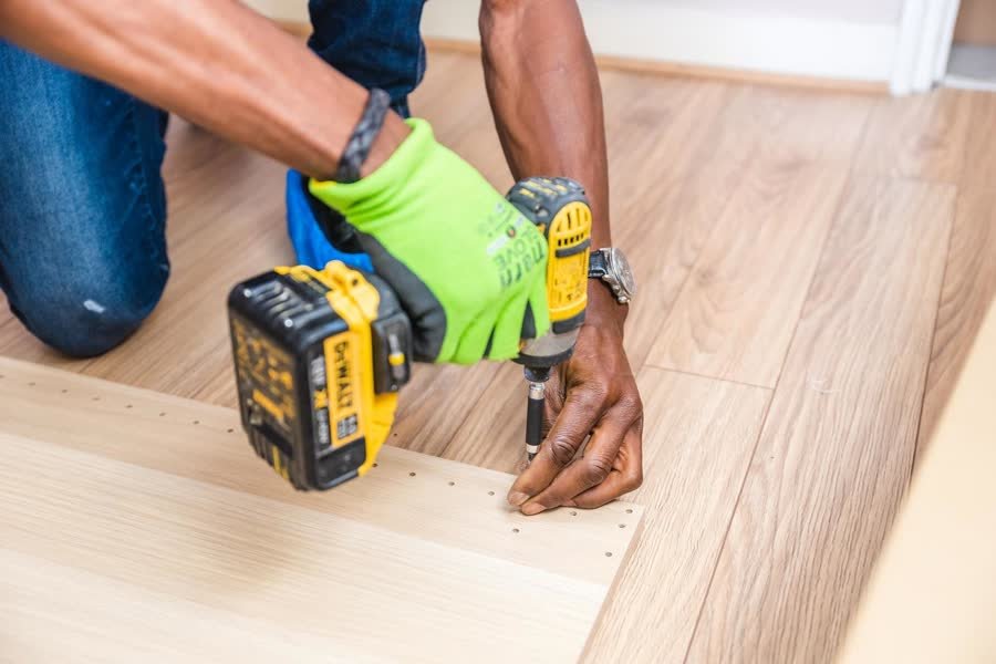 Installer securing a laminate floor plank with a drill