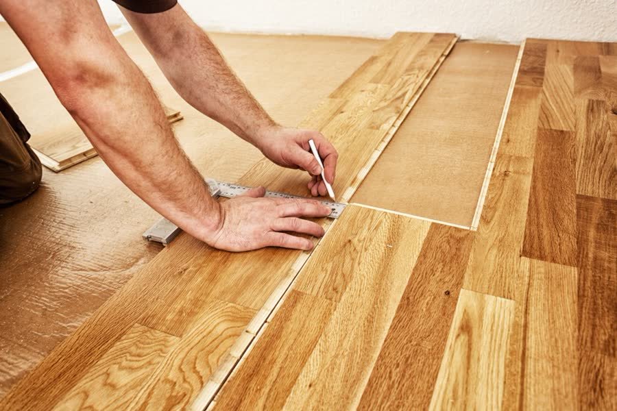 Installer marking a timber floor plank during installation