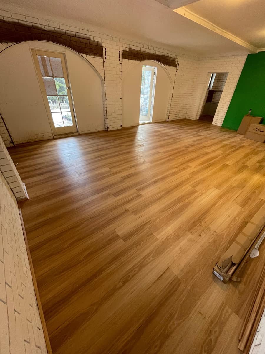 Completed flooring in an open-plan living space with brick feature wall